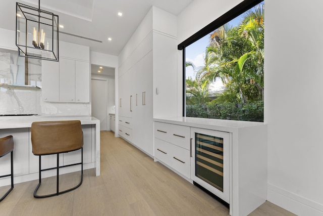 interior space featuring pendant lighting, backsplash, white cabinetry, and wine cooler