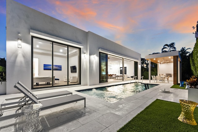 pool at dusk featuring a patio area