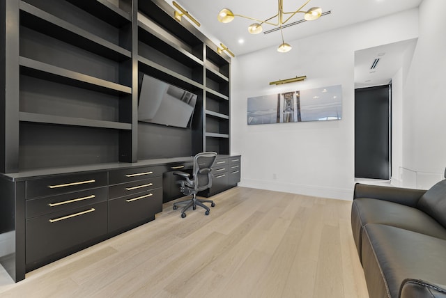 home office with built in shelves, light hardwood / wood-style floors, and an inviting chandelier