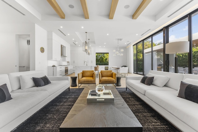 living room with beamed ceiling, dark hardwood / wood-style flooring, a notable chandelier, and sink