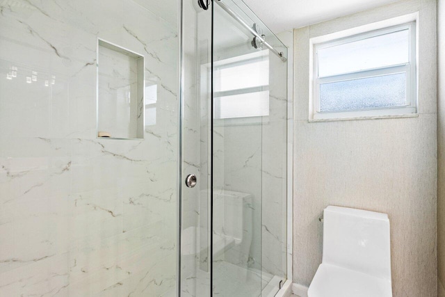 bathroom featuring a shower with shower door and toilet