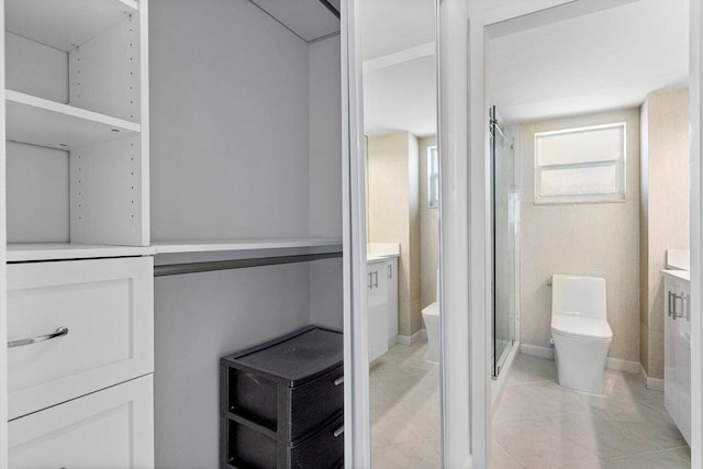 bathroom with a shower with door, vanity, and toilet