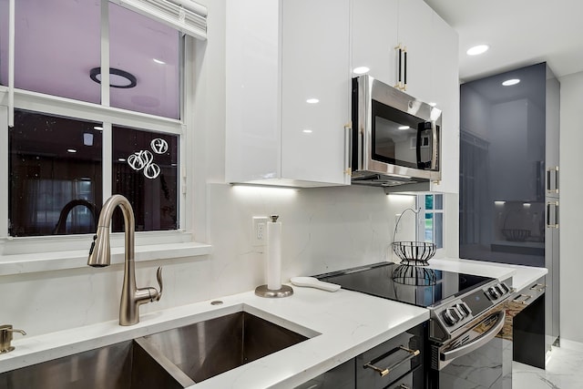 kitchen featuring light stone countertops, stainless steel appliances, white cabinetry, and sink