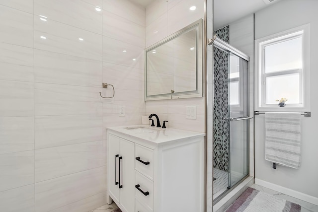 bathroom featuring vanity, a shower with shower door, and tile walls