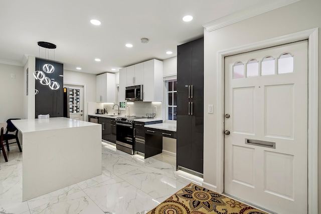 kitchen featuring sink, hanging light fixtures, appliances with stainless steel finishes, a kitchen island, and white cabinetry