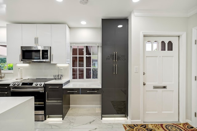 kitchen with light stone counters, crown molding, white cabinetry, and stainless steel appliances