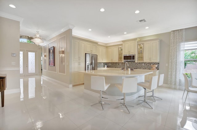 kitchen with sink, backsplash, an island with sink, a kitchen bar, and appliances with stainless steel finishes