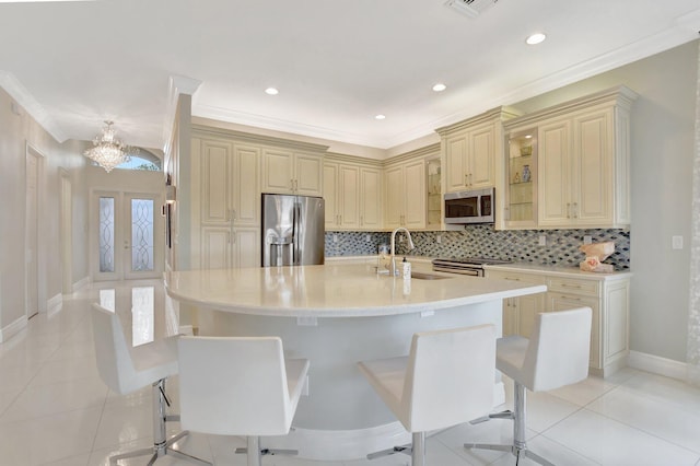 kitchen with french doors, sink, a breakfast bar area, an island with sink, and stainless steel appliances