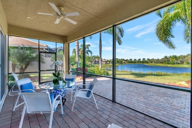 sunroom featuring ceiling fan and a water view