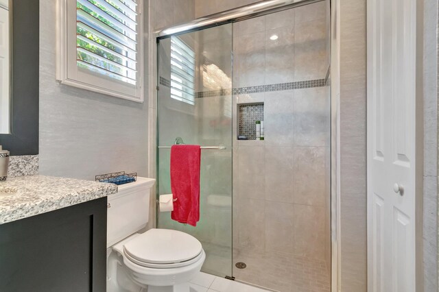 bathroom with tile patterned flooring, vanity, an enclosed shower, and toilet