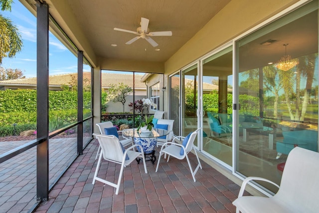 sunroom / solarium featuring ceiling fan with notable chandelier