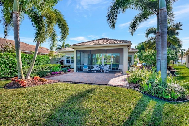 rear view of house featuring a sunroom, a yard, and a patio