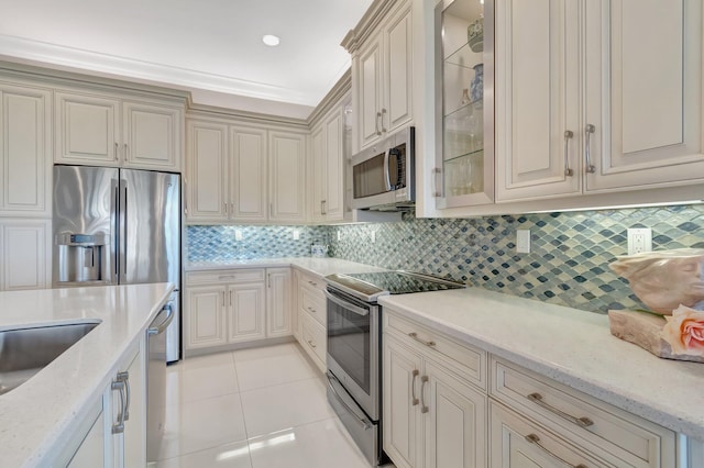 kitchen with light stone countertops, light tile patterned floors, backsplash, and stainless steel appliances