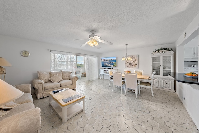 living room with a textured ceiling and ceiling fan with notable chandelier