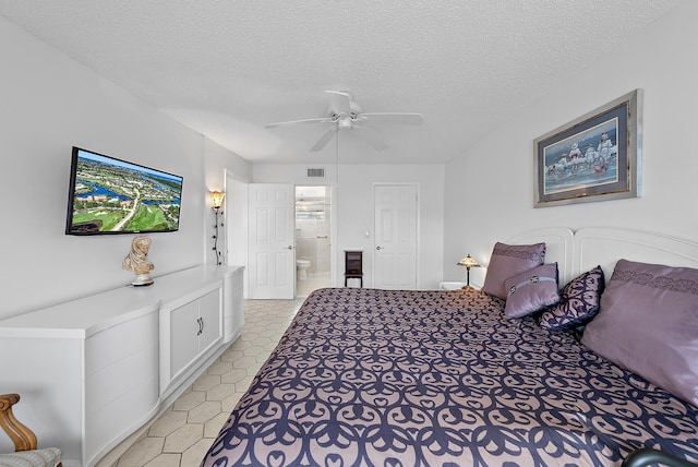 bedroom with ceiling fan, light tile patterned floors, a textured ceiling, and connected bathroom