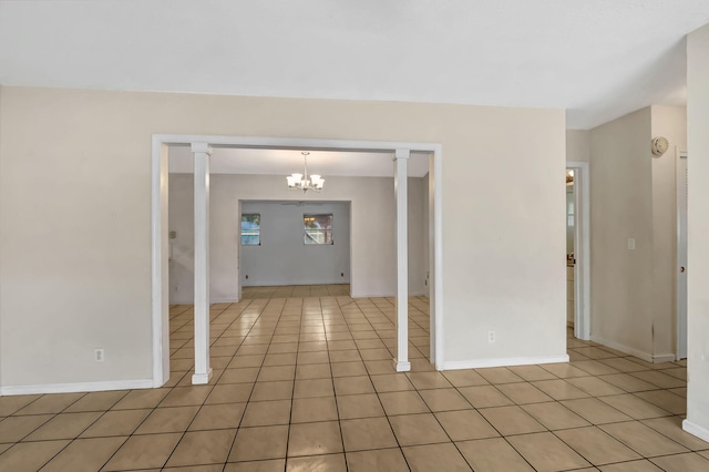 tiled spare room featuring a notable chandelier