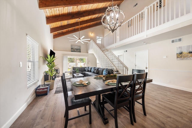 dining area with ceiling fan with notable chandelier, a high ceiling, and wood-type flooring