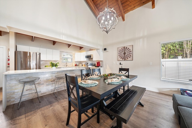 dining space with wood ceiling, a chandelier, light wood-type flooring, beamed ceiling, and high vaulted ceiling