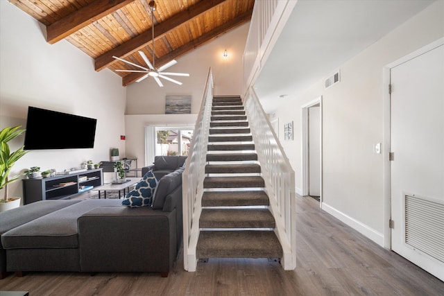 stairway with hardwood / wood-style floors, wooden ceiling, ceiling fan, high vaulted ceiling, and beam ceiling