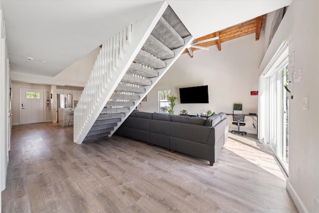 living room with light wood-type flooring, a wealth of natural light, and beamed ceiling