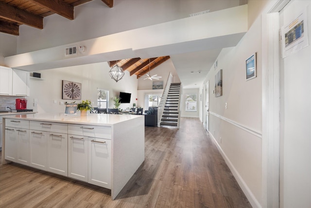 kitchen featuring white cabinetry, light hardwood / wood-style floors, ceiling fan with notable chandelier, lofted ceiling with beams, and wood ceiling