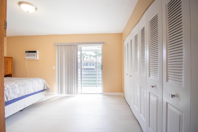 bedroom with light wood-type flooring and a wall unit AC