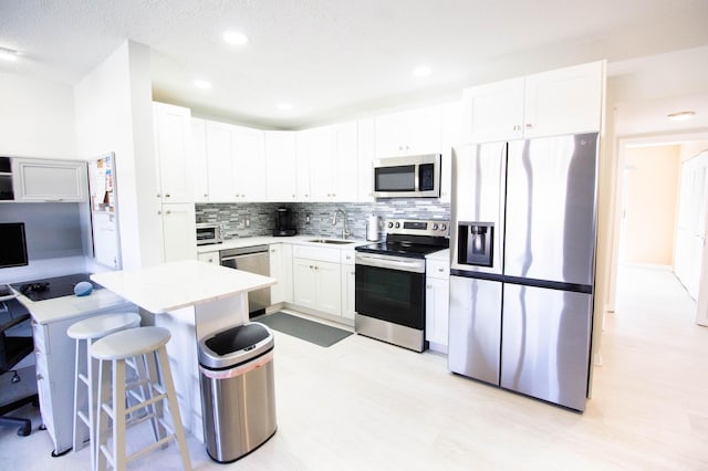 kitchen with backsplash, sink, a textured ceiling, white cabinetry, and stainless steel appliances