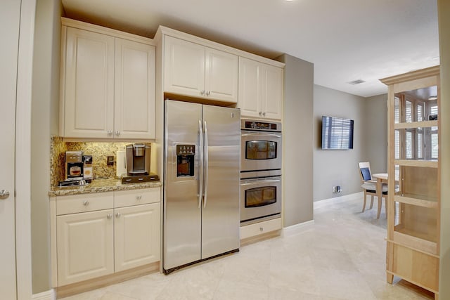 kitchen featuring backsplash, white cabinetry, light stone countertops, and stainless steel appliances