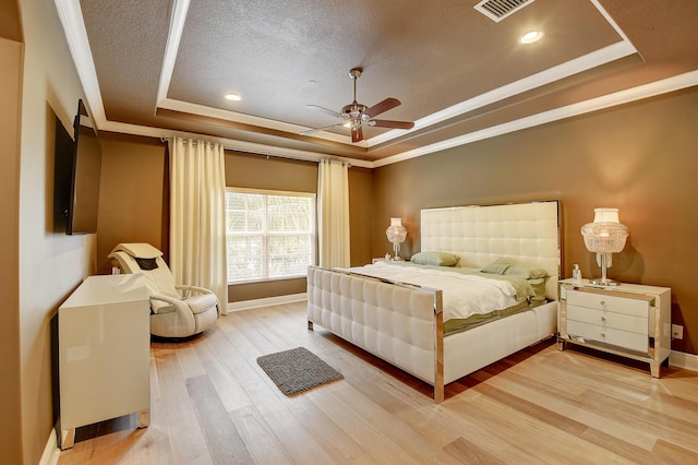 bedroom with ceiling fan, ornamental molding, a textured ceiling, a tray ceiling, and wood-type flooring