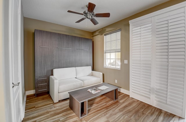 living room with a textured ceiling, light wood-type flooring, and ceiling fan