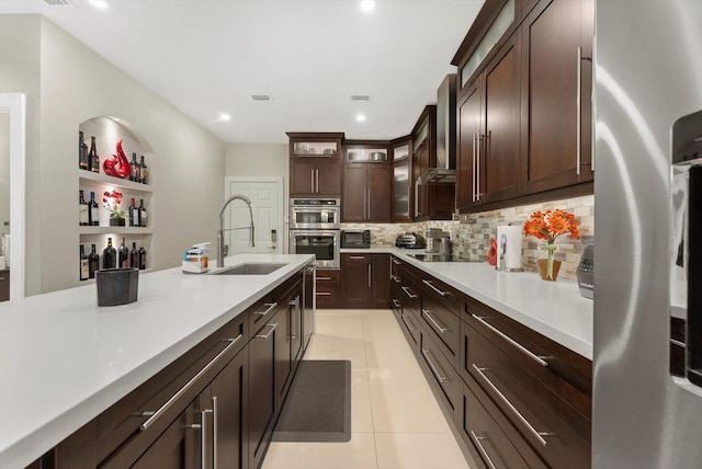 kitchen with dark brown cabinets, sink, wall chimney range hood, and appliances with stainless steel finishes