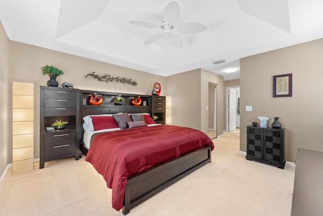 carpeted bedroom with a raised ceiling and ceiling fan