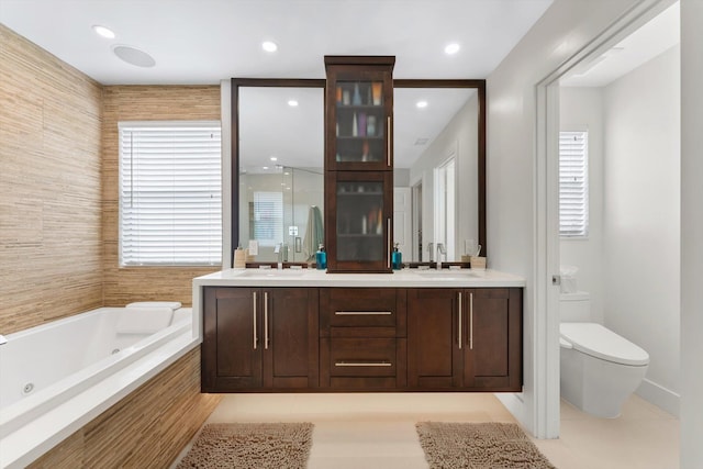 bathroom featuring tile patterned floors, vanity, tiled bath, and toilet