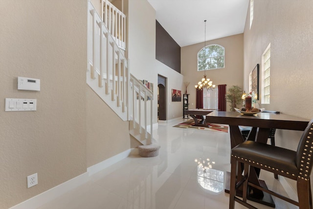 entrance foyer featuring light tile patterned floors, billiards, an inviting chandelier, and a high ceiling