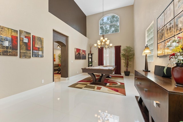 tiled dining space with a notable chandelier, a towering ceiling, and pool table