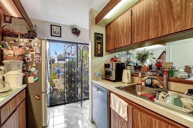 kitchen featuring light tile patterned floors, a textured ceiling, and appliances with stainless steel finishes