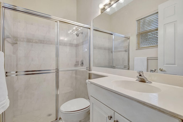 bathroom featuring vanity, a shower with shower door, and toilet