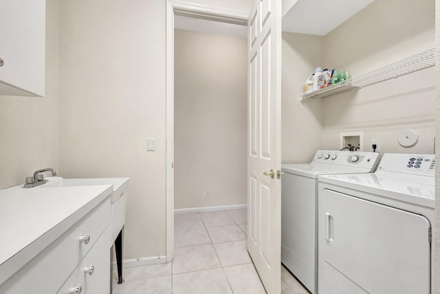 laundry room featuring light tile patterned floors, washing machine and dryer, and cabinets