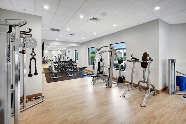 gym with a drop ceiling and light hardwood / wood-style floors