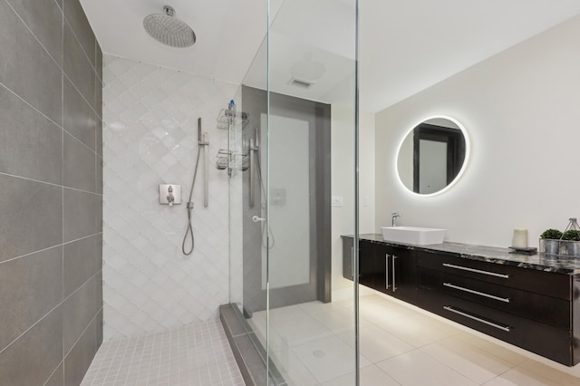 bathroom with tile patterned flooring, vanity, and a tile shower