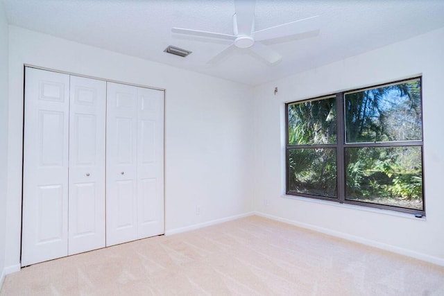 unfurnished bedroom featuring ceiling fan, a closet, and light colored carpet