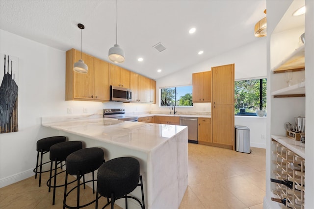 kitchen featuring lofted ceiling, a breakfast bar area, decorative light fixtures, kitchen peninsula, and stainless steel appliances