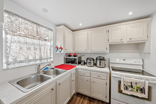 kitchen with dark hardwood / wood-style floors, white cabinetry, electric stove, and sink