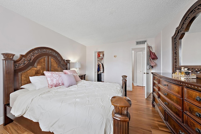 bedroom featuring a textured ceiling, light hardwood / wood-style flooring, and a closet