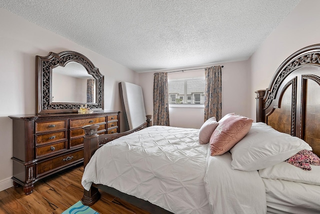 bedroom with a textured ceiling and dark hardwood / wood-style flooring