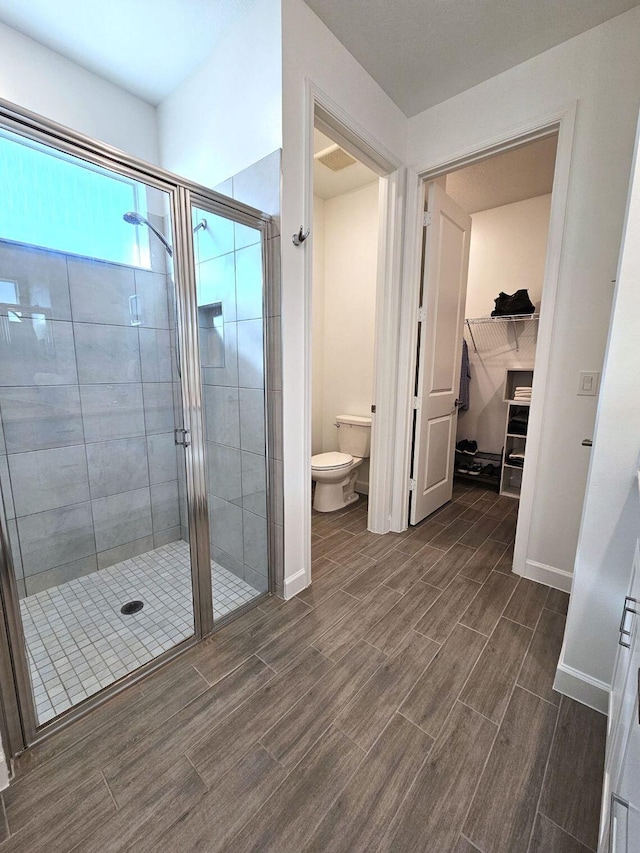 bathroom with toilet and a shower with shower door