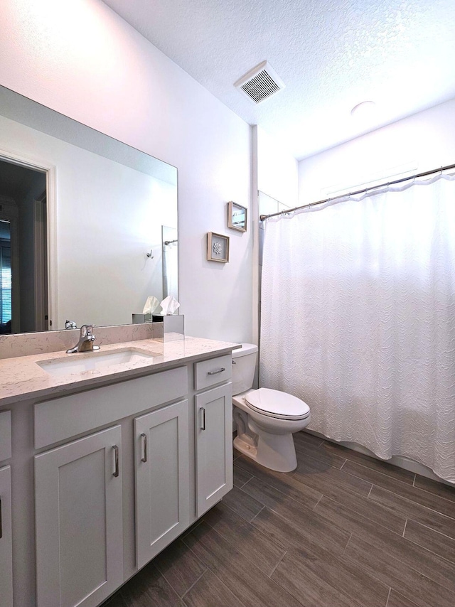 bathroom featuring vanity, a textured ceiling, hardwood / wood-style flooring, and toilet