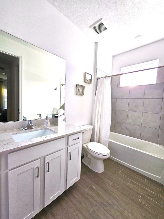 full bathroom with shower / bath combo, vanity, a textured ceiling, wood-type flooring, and toilet