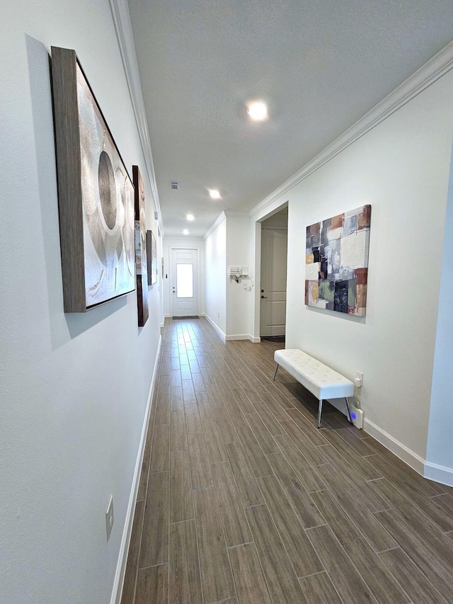 hallway with ornamental molding, a textured ceiling, and dark wood-type flooring