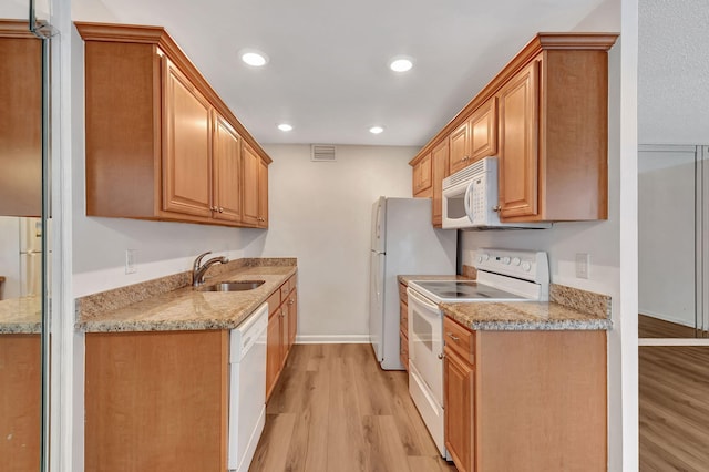 kitchen featuring light stone counters, sink, light hardwood / wood-style floors, and white appliances